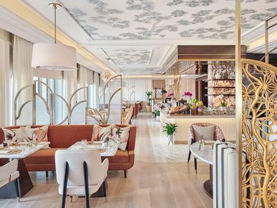 Helles, elegantes Restaurant mit filigranem Raumteiler und Blumen auf Tischen und Tresen