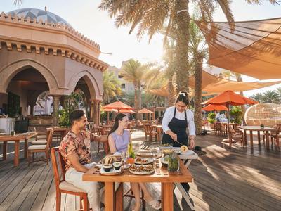 Paar genießt im Freien Essen unter Palmen in einem luxuriösen, sonnigen Restaurant.