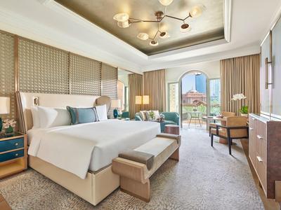 Elegantes Hotelzimmer mit Kingsize-Bett, Sitzbereich und Balkon mit Aussicht.