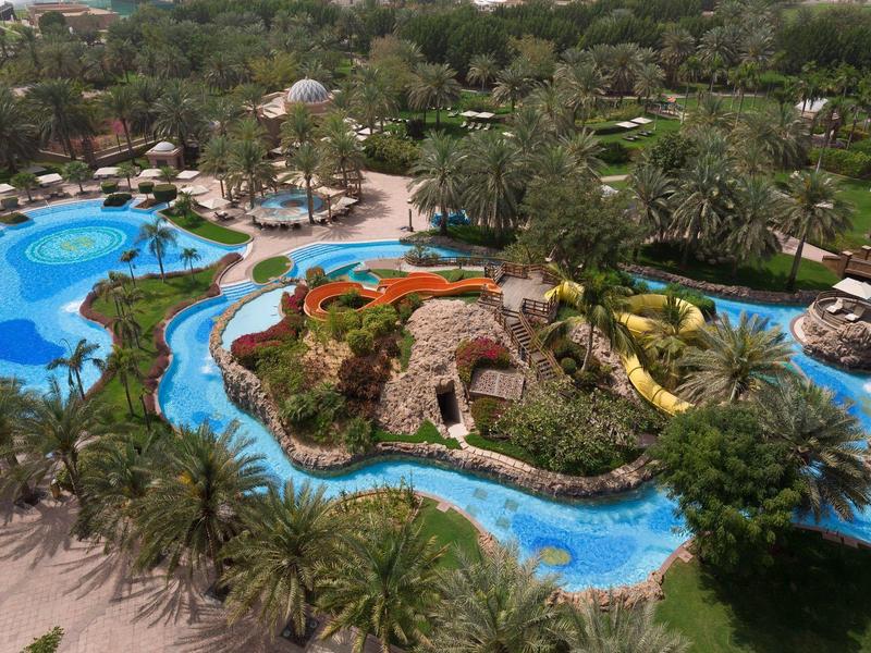 Resort mit Poollandschaft, Wasserbahn und üppiger tropischer Vegetation.