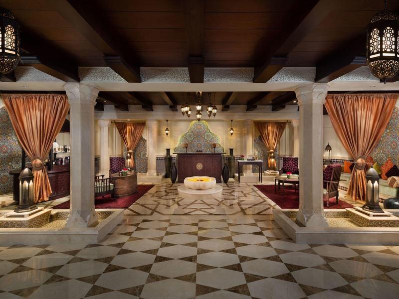 Luxuriöse Hotellobby mit Mosaikboden, dekorativen Vorhängen, Holzdecken und warmem Licht.