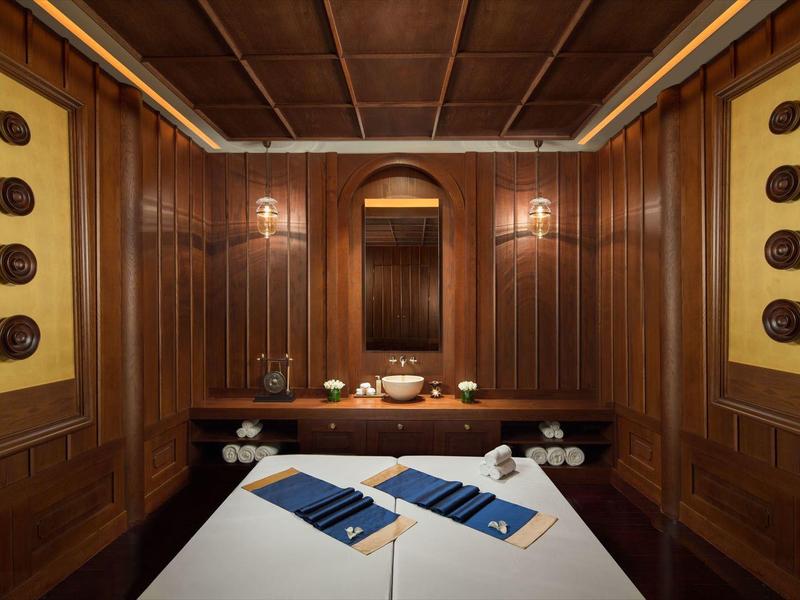 Schlicht eingerichteter Massageraum mit Holzwänden, Decke und weißen Behandlungsbetten.