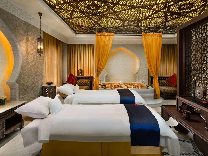 Luxuriöses Hotelzimmer mit zwei Einzelbetten, orientalischem Dekor und warmem Licht.