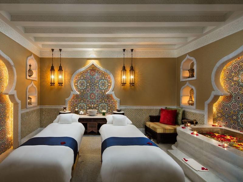 Luxuriöser Wellnessraum mit orientalischem Design, zwei Massageliegen und warmem Licht.
