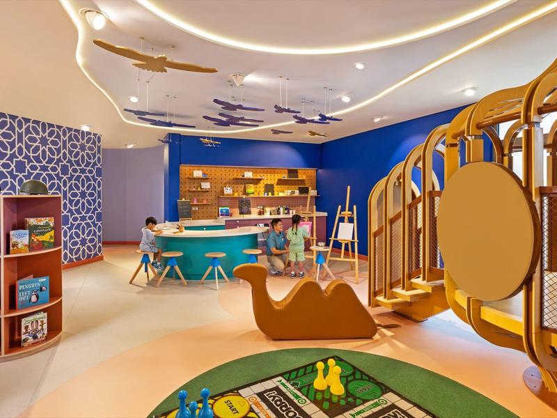 Bunter Kinderspielraum mit Kletterstruktur, Spielzeug und Basteltisch in einem Hotel.