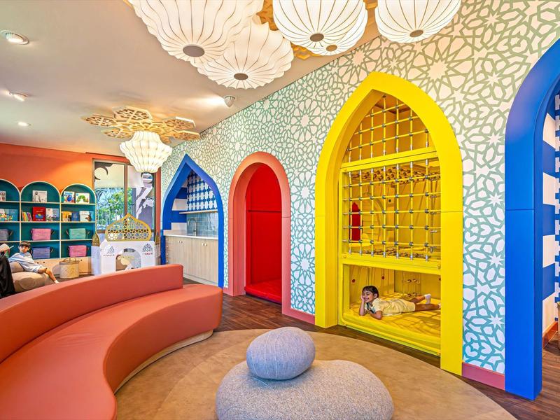 Bunte Hotellobby mit gebogenen Sitzbänken und orientalisch inspirierten Durchgängen.