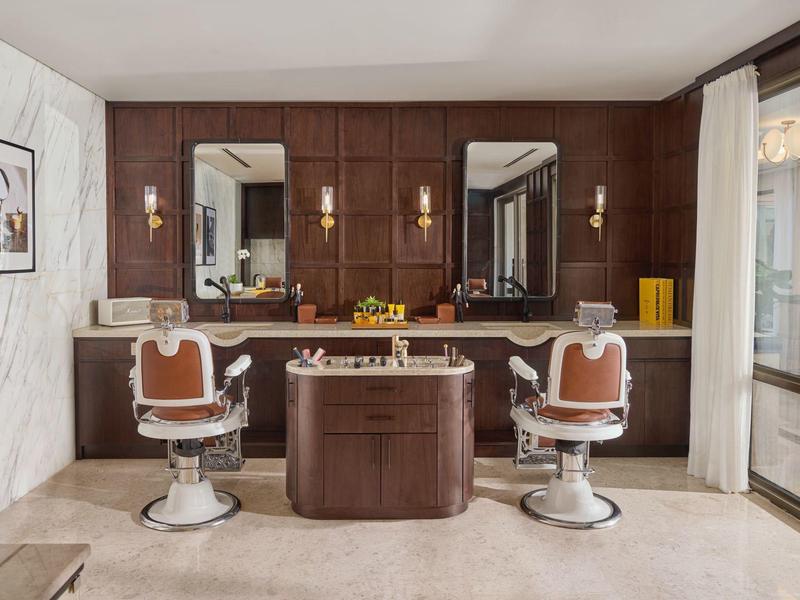 Eleganter Friseurbereich mit zwei Stühlen, Spiegeln und hochwertigen Holzmöbeln in einem Hotel.