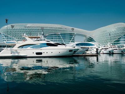 Luxusyachten liegen im Hafen vor modernen, geschwungenen Gebäuden unter klarem Himmel.