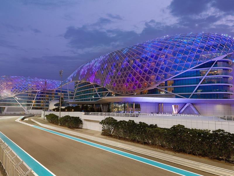 Moderne Gebäude mit geschwungener Glasfassade und blauer Beleuchtung bei Dämmerung.