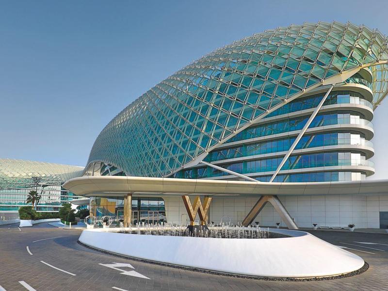 Moderne gebogene Glas- und Stahlstruktur mit futuristischem Design bei klarem Himmel.