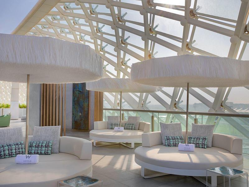 Moderner, heller Lounge-Bereich mit runden Sofas, großen Lampenschirmen und Glasfront mit Stahlrahmen.