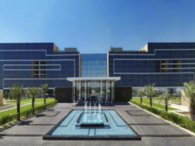 Moderne Bürogebäude mit Glasfront, großem Wasserbecken und gepflegtem Garten im Vordergrund.