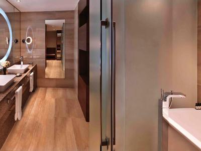 Modernes Badezimmer mit Holzakzenten, freistehender Badewanne und beleuchtetem Spiegel.