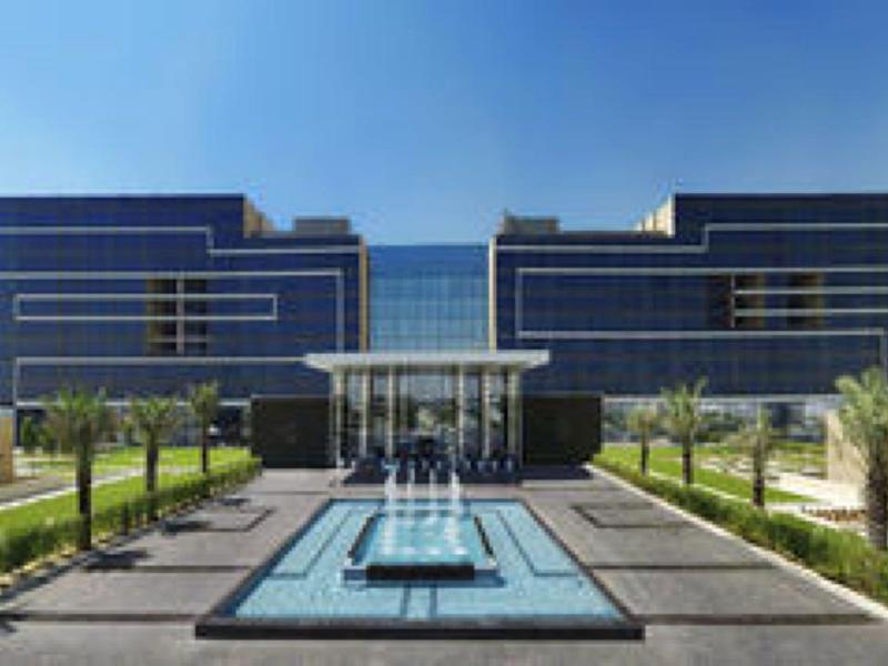 Moderne Bürogebäude mit Glasfront, großem Wasserbecken und gepflegtem Garten im Vordergrund.