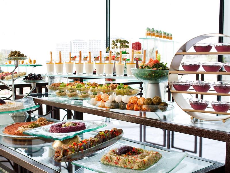 Buffet mit vielen Desserts, Obst und kleinen Häppchen auf mehrstöckigen Glastischen.