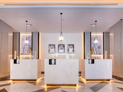 Moderner Empfangsbereich mit drei Tresen, Pendelleuchten und Dekorationsbildern an der Wand.