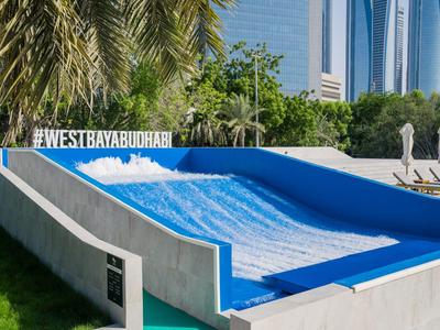 Wellenrutsche im Freien mit blauer Oberfläche und Palmen im Hintergrund in einem Hotelressort.
