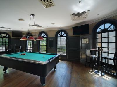 Gemütlicher Billardraum mit Holzboden, grüner Tischfläche und großen Fenstern.