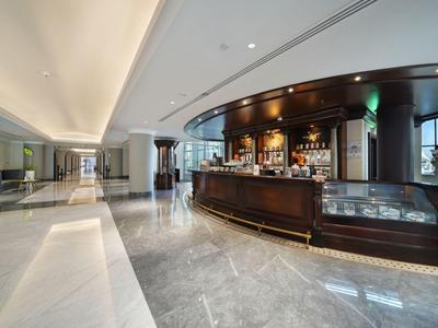 Moderner Hotelbarbereich mit elegantem Holzbar und glänzendem Marmorboden.