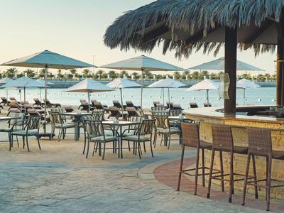 Offene Strandbar und Sitzbereich mit Stühlen und Tischen nahe Wasser und Sonnenschirmen