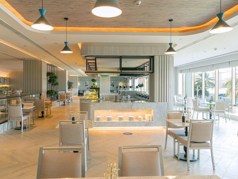 Helles modernes Café mit großen Fenstern, bequemen Stühlen und warmen Deckenleuchten.