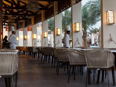 Moderner Außenbereich eines Restaurants mit gedeckten Tischen und Köchen in weißen Uniformen.