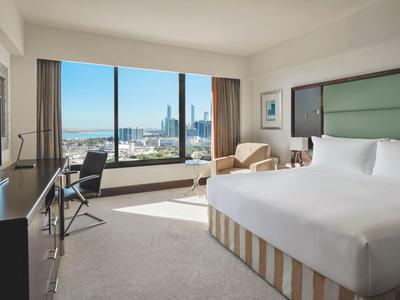 Modernes Hotelzimmer mit großem Fenster, Schreibtisch, Stuhl und bequemem Doppelbett.