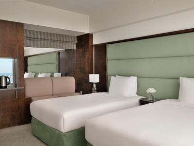 Hotelzimmer mit zwei Einzelbetten, grünem Kopfteil und braunen Wandpaneelen.