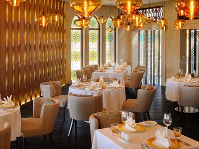 Elegantes Restaurant mit weißen Tischdecken, bequemen Stühlen und warmem Licht.