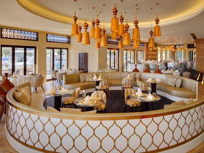 Elegantes rundes Restaurant mit cremefarbenen Polstern und dekorativen hängenden Lampen.