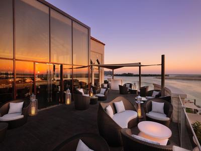 Dachterrasse mit gemütlichen Sitzgruppen und Meerblick bei Sonnenuntergang.