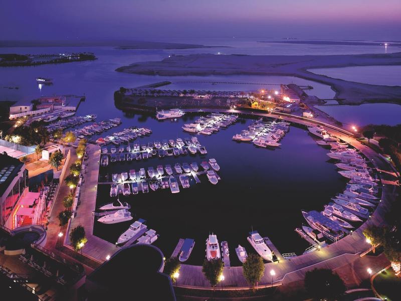 Offener Sitzbereich eines Restaurants mit Blick auf moderne Wolkenkratzer bei Sonnenuntergang.