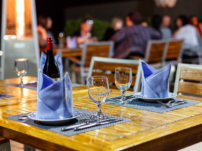 Eleganter Holztisch mit blau gefalteten Servietten und Weingläsern in einem Restaurant