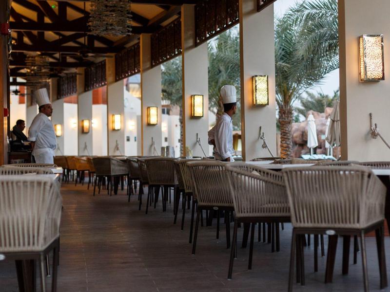 Moderner Außenbereich eines Restaurants mit gedeckten Tischen und Köchen in weißen Uniformen.