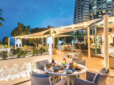 Abendliche Terrasse eines Hotels mit gedeckten Tischen und moderner Beleuchtung.