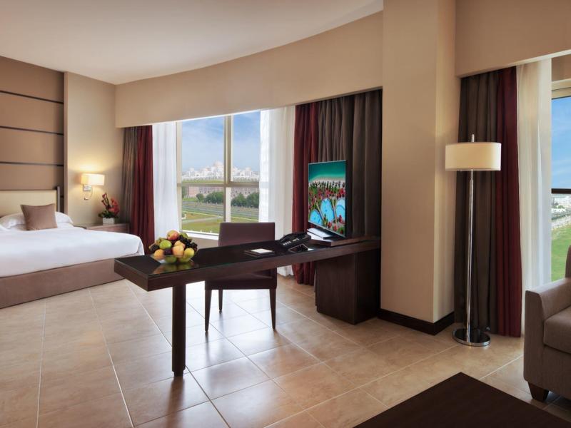 Helles Hotelzimmer mit Doppelbett, Schreibtisch, TV, Fenster mit Meerblick und gemütlicher Sitzecke.