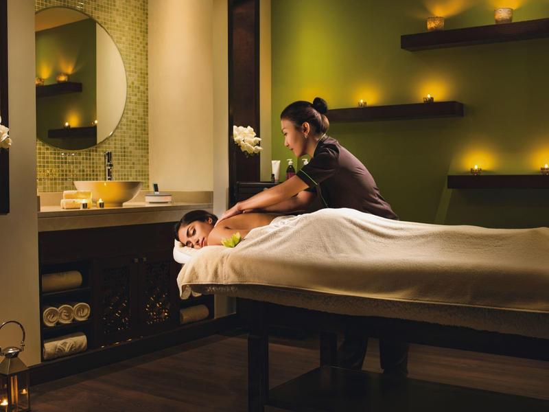 Eine entspannte Massage in einem warm beleuchteten, gemütlichen Spa-Raum mit Kerzen.