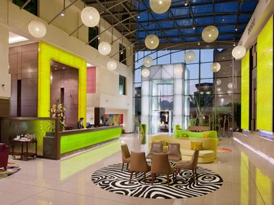 Moderna hall d'hotel con mobili colorati, luci sospese e tetto in vetro