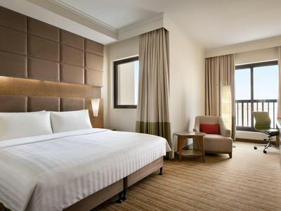 Modernes Hotelzimmer mit großem Bett, Sessel, Schreibtisch und Balkon mit Aussicht.