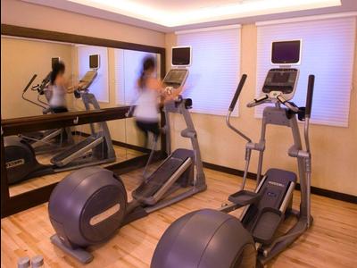 Moderner Fitnessraum mit Laufbändern, Crosstrainern und Holzfußboden in einem Hotel.