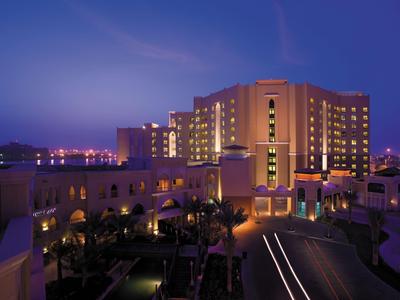 Beleuchtetes Hotelgebäude bei Nacht mit klarer blauer Dämmerung am Himmel.