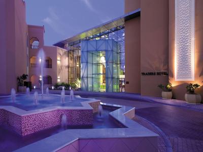 Moderner Hotelbereich mit beleuchtetem Brunnen und Glasfassade bei Dämmerung.