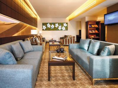 Gemütliches Wohnzimmer mit zwei blauen Sofas, Teppich, Holztisch und moderner Wanddekoration.