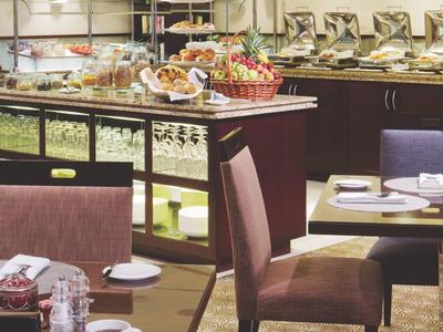 Buffetraum mit gedeckten Tischen, braunen Stühlen und verschiedenen Speisen auf einem Buffet.