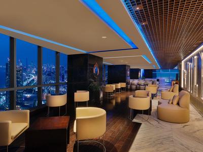 Elegante Hotellounge mit modernen Sitzgelegenheiten und Panoramablick auf die Stadt bei Nacht.