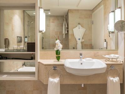 Modernes Hotelbadezimmer mit großem Spiegel, Waschbecken, Dusche und eleganter Beleuchtung.