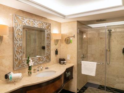 Modernes Hotelbadezimmer mit großer Dusche, Marmorwänden und elegantem Spiegelrahmen.