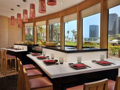 Modernes Restaurant mit großer Fensterfront, Holzmöbeln und Blick auf Außenanlagen.