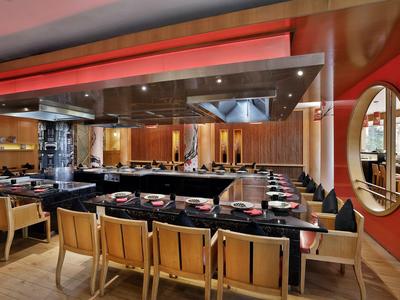 Modernes Restaurant mit Thekenplätzen, roten Wänden und Holzstühlen in einem Hotel.