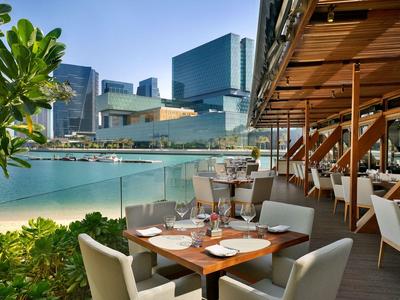 Offenes Restaurant auf einer Terrasse mit Stadtblick und modernem Ambiente.